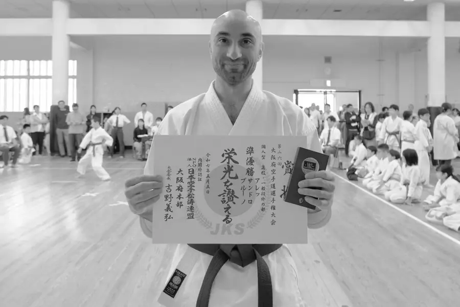 Allievo in karategi mostra un attestato con calligrafia giapponese